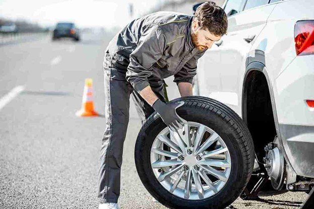 Driver safely on the roadside with a warning triangle placed in front of a broken-down car.