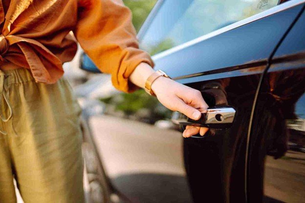 Driver waiting safely on the roadside with a warning triangle placed behind a broken-down car.