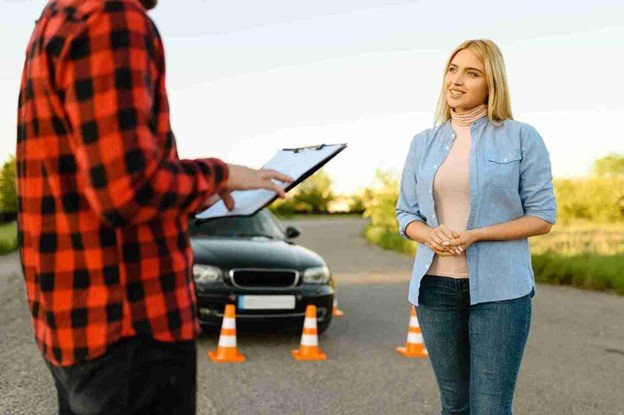 Driver speaking with a roadside assistance worker next to a disabled car with safety cones