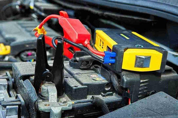 Connecting jumper cables to a car battery inside the engine bay