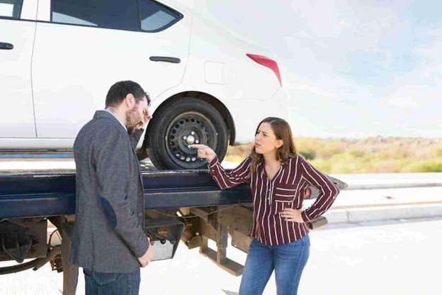 White car pickup truck loaded on a flatbed tow truck