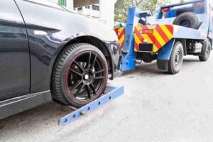 Wheel-lift tow truck lifting and securing the front wheels of a car for roadside towing service