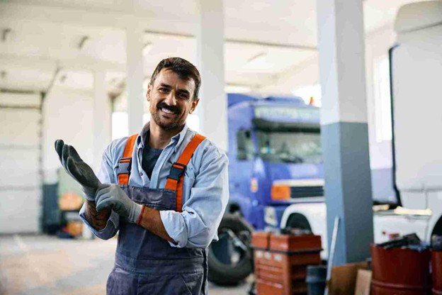 Professional towing technician wearing work gloves and safety gear inside a service garage
