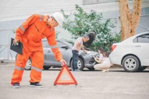 Roadside worker placing a reflective warning triangle behind stopped vehicles