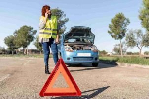 Roadside worker placing a reflective warning triangle behind stopped vehicles