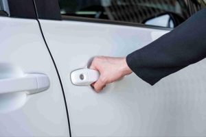 Close-up of a hand pulling the handle of a white car door