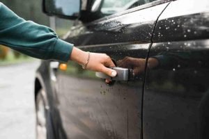 Close-up of a hand pulling a car door handle on a parked vehicle