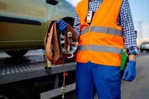 Driver sitting beside a broken-down car waiting for roadside assistance