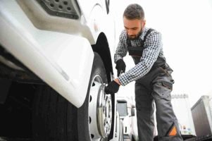 Mechanic wearing work gloves tightening lug nuts on a truck wheel using a wrench