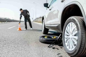 Technician using a jack to lift a vehicle during a tire change