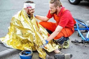 A worker of emergency towing is taking care of the man who has been car accident